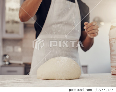 Chef man and flour sprinkle on dough for baking preparation work and process at culinary counter. Restaurant worker in professional kitchen preparing wheat bread, cake or pizza recipe. Chef man and flour sprinkle on dough for baking preparation work and process at culinary counter. Restaurant worker in professional kitchen preparing wheat bread, cake or pizza recipe. 107569427