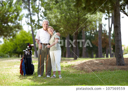 Portrait, smile or happy old couple on golf course in fitness workout, exercise or round together on grass. Embrace, healthy elderly man hugging or smiling in golfing sports game with senior woman 107569559