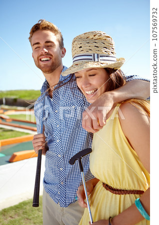 Happy couple, mini golf and hug on summer date, fun activity and freedom in sunshine. Man, woman and young people playing outdoor games with love, happiness and quality time together on sunny day Happy couple, mini golf and hug on summer date, fun activity and freedom in sunshine. Man, woman and young people playing outdoor games with love, happiness and quality time together on sunny day 107569732