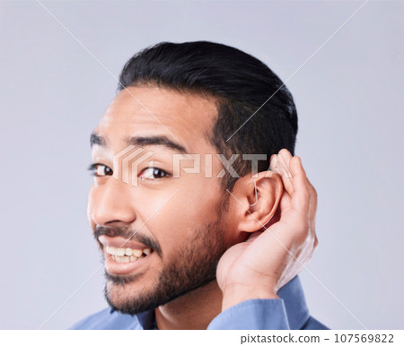 Deaf, portrait and asian man with hand on cochlear in studio for speak up, listen or communication on grey background. Hearing aid, face and Japanese guy with a disability, emoji and sign for implant 107569822