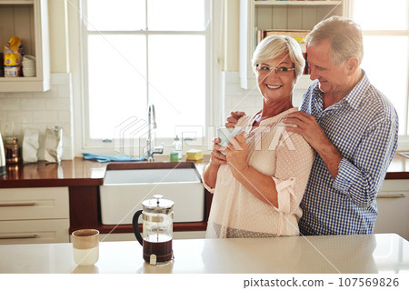 Happy, coffee or old couple hugging in kitchen at home bonding or enjoying quality morning time together. Embrace, retirement or lovely senior man talking, relaxing or drinking tea with mature woman 107569826