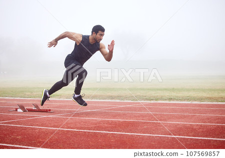 The perfect getaway. Full length shot of a handsome young male athlete running on an outdoor track. The perfect getaway. Full length shot of a handsome young male athlete running on an outdoor track. 107569857