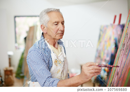 The creative adult is the child who survived. Shot of a senior man working on a painting at home. The creative adult is the child who survived. Shot of a senior man working on a painting at home. 107569880