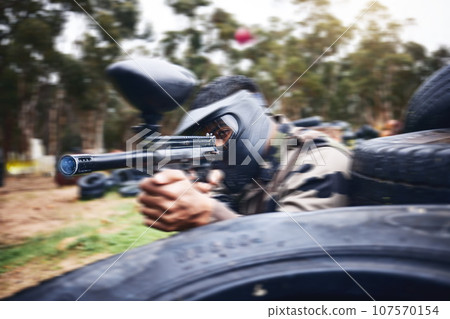 Paintball, gun or man playing a shooting game with fast action on a fun battlefield on holiday. Military mission, fitness or player aiming with weapons gear for war survival in an outdoor competition 107570154