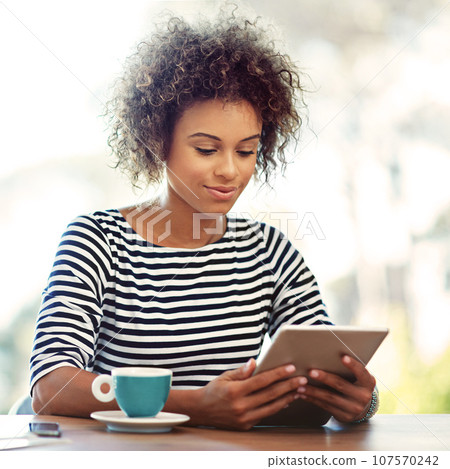 This makes doing business so easy. Shot of a young woman working at home with a digital tablet. 107570242