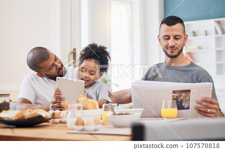 Gay parents, morning and breakfast with child in a home with reading and tablet with dad. Food, house and family with bonding, care and love together at dining table with paper and tech with kid Gay parents, morning and breakfast with child in a home with reading and tablet with dad. Food, house and family with bonding, care and love together at dining table with paper and tech with kid 107570818