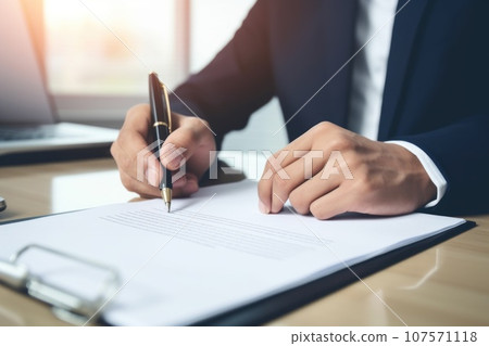 Close up a hand signing the document at the table on office room Close up a hand signing the document at the table on office room 107571118