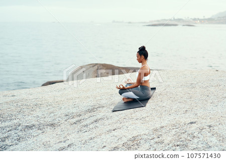 Yoga, meditation and woman on a beach with lotus pose, wellness and fitness. Pilates, sea and female person on sand with peace in nature feeling relax and calm with spiritual and holistic mockup 107571430