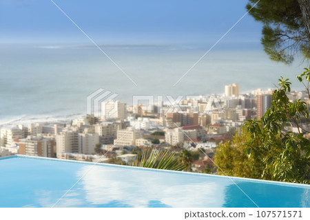 Scenic view of infinity swimming pool overlooking Sea Point in Cape Town, South Africa with ocean background. Luxury outdoor desk, rooftop feature in a condo, home, hotel. Cityscape, skyline of city 107571571