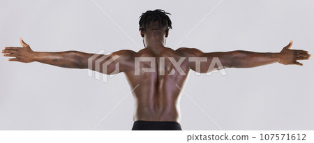 Back, arms and muscular with a model black man posing in studio on a gray background for fitness or exercise. Muscle, health and wellness with a strong male athlete standing or flexing for power 107571612