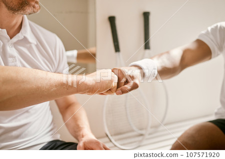 Sports, hands and fist bump by men friends at indoor tennis court for support, motivation or training closeup. Zoom, emoji and people with fitness deal, workout or partnership agreement or solidarity 107571920
