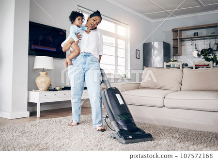 She does it all. Shot of a young mother using a cellphone while completing housework and holding her baby at home. 107572168
