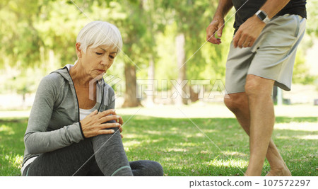 Old couple, woman with knee pain and injury outdoor, fibromyalgia health problem and joint ache from exercise. Muscle tension, arthritis and people in retirement with fitness in park and emergency 107572297