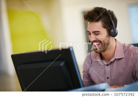 Quality is the best business plan. Shot of a friendly young call centre agent sitting at his desk. Quality is the best business plan. Shot of a friendly young call centre agent sitting at his desk. 107572392