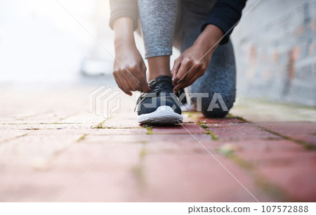 Exercise, tie and and laces of female athlete or running shoes or hands and healthy woman with knee on the floor. Training, work out and foot or lady runner starts fitness routine in closeup Exercise, tie and and laces of female athlete or running shoes or hands and healthy woman with knee on the floor. Training, work out and foot or lady runner starts fitness routine in closeup 107572888
