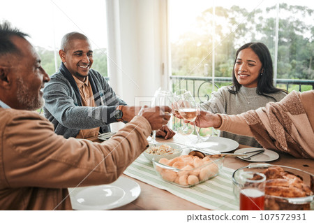 Wine, food and toast with family at dining table for party, celebration and holiday. Lunch, happy and success with group of people and cheers with glass at home for event, support or dinner together Wine, food and toast with family at dining table for party, celebration and holiday. Lunch, happy and success with group of people and cheers with glass at home for event, support or dinner together 107572931