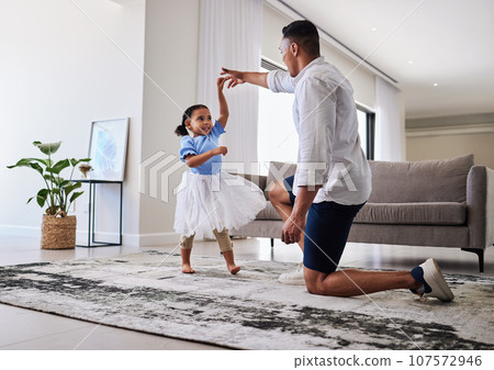Family, father and daughter dancing for fun, energy and love in the living room feeling happy holding hands to dance at home. Man or dad and girl child moving to favorite song on fathers day in house Family, father and daughter dancing for fun, energy and love in the living room feeling happy holding hands to dance at home. Man or dad and girl child moving to favorite song on fathers day in house 107572946