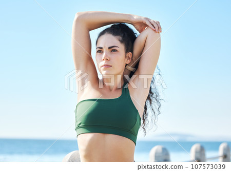 Exercise, arm stretching and fitness by woman at beach for run, sports and cardio on blue sky background. Mindset, stretch and workout by girl at ocean for training, calm or relax, warm up or routine 107573039