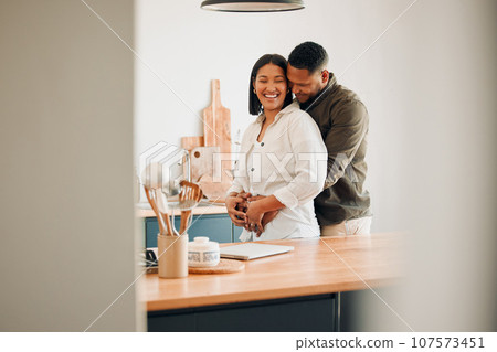 Hugging, happy and excited couple spending quality time together and relaxing at home. Loving, relaxed and affectionate African lovers embracing, cuddling and having fun in the house 107573451
