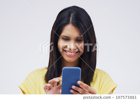 Typing, smile and woman with a cellphone, connection and network against a white studio background. Female person, girl or model with a smartphone, online reading or search internet with website info 107573881