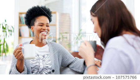 Coffee, funny and woman friends laughing on a sofa in the living room of their home together to relax. Smile, tea and happy young women talking in an apartment while drinking a comfort beverage 107575766