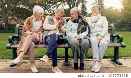 Conversation, bonding and senior friends in a park sitting on bench for fresh air together. Happy, smile and group of elderly people in retirement in discussion or talking in an outdoor green garden. 107575818