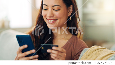 Woman, phone or credit card for ecommerce, online shopping or bank app in Colombian house living room or home sofa. Smile, happy and relax customer on fintech technology or e commerce retail software 107576098