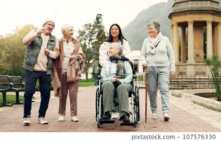 Retirement, walking and elderly friends in park for bonding, wellness and quality time together outdoor. Wheelchair, health and senior man and women with caregiver for fresh air, nature and relax Retirement, walking and elderly friends in park for bonding, wellness and quality time together outdoor. Wheelchair, health and senior man and women with caregiver for fresh air, nature and relax 107576330