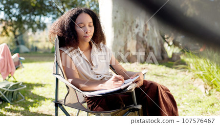 Camping, morning and a woman writing in a book for travel notebook, journal or summer memory. Relax, reading and a girl or person in a chair while on a camp or document for holiday goals in nature Camping, morning and a woman writing in a book for travel notebook, journal or summer memory. Relax, reading and a girl or person in a chair while on a camp or document for holiday goals in nature 107576467