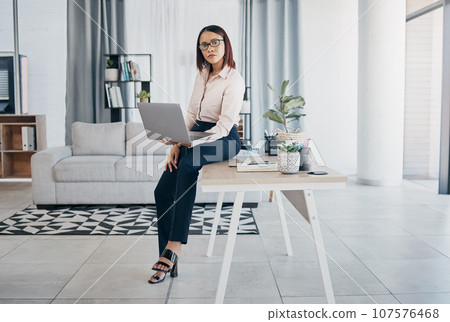 Portrait, woman and office with laptop, working and thinking in corporate clothes, alone and serious. Sitting on desk, virtual meeting and writing report for client review and business manager stats Portrait, woman and office with laptop, working and thinking in corporate clothes, alone and serious. Sitting on desk, virtual meeting and writing report for client review and business manager stats 107576468