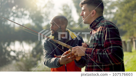 Fishing, lake and friends in nature talking on holiday, adventure and vacation together outdoors. Friendship, conversation and men with rods by river for sports hobby, activity and catching fish 107576603