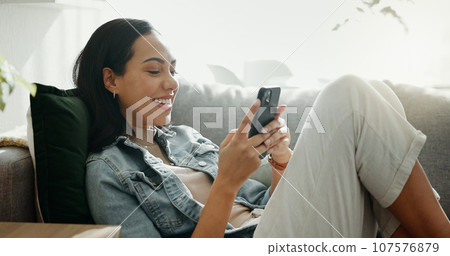 Woman, phone texting and home with social media post, networking and online on a sofa. Mobile app, happy message and typing on a living room couch with digital entertainment and tech in a house Woman, phone texting and home with social media post, networking and online on a sofa. Mobile app, happy message and typing on a living room couch with digital entertainment and tech in a house 107576879