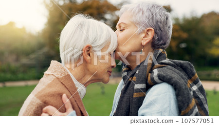 Senior woman kissing her friend on the forehead for affection, romance and bonding on outdoor date. Nature, commitment and elderly female couple in retirement with intimate moment in garden or park. Senior woman kissing her friend on the forehead for affection, romance and bonding on outdoor date. Nature, commitment and elderly female couple in retirement with intimate moment in garden or park. 107577051