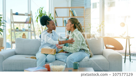Sad women, friends and support on sofa in home, care and conversation for anxiety. African girls, depression and comfort on couch for kindness, empathy and help to console in communication together 107577129