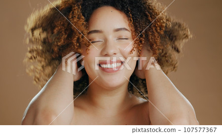 Happy woman, curly hair or natural beauty dermatology for wellness in studio with smile or skin glow. Face, smile or confident biracial female person with skincare cosmetics on a brown background Happy woman, curly hair or natural beauty dermatology for wellness in studio with smile or skin glow. Face, smile or confident biracial female person with skincare cosmetics on a brown background 107577367