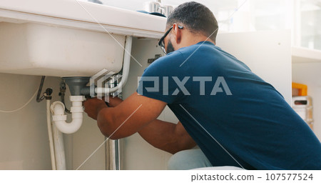 Plumber black man, kitchen and sink maintenance with tools, focus and pipe repair for drainage in home. Entrepreneur handyman, plumbing expert or small business owner in house for fixing water system 107577524