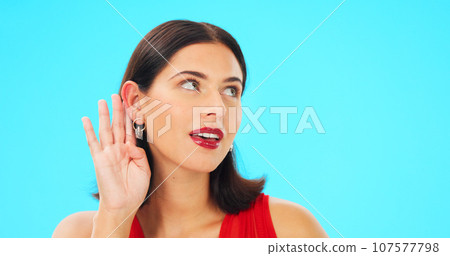 Secret, gossip and woman in blue studio background for beauty and listening. Whisper, frame and privacy with makeup, headshot and isolated for cupping ear, rumour and thinking for spy, emoji or talk 107577798