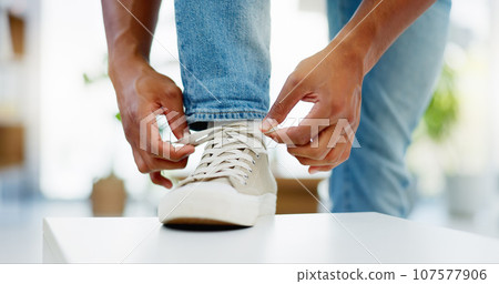 Hands, tie shoes and lace in home to get ready to start walking, travel or journey in house. Hand of man, person tying laces and sneakers, footwear or shoe in preparation for walk, trip or running. 107577906