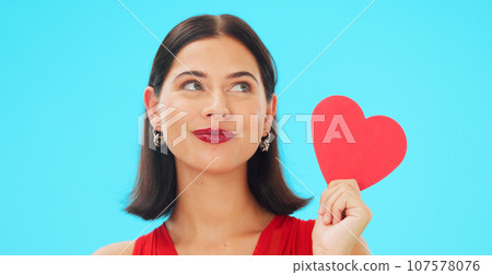 Thinking, happy and woman with paper heart in studio isolated on a blue background mockup. Idea, romance and model with love sign for anniversary, emoji and smile for valentines day gift or present 107578076