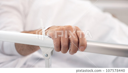 Hand on rail, patient and hospital bed for healthcare, wellness and healing in clinic after cancer surgery. Medical treatment, sick and person in bedroom with health problem in hospice of clinic 107578440