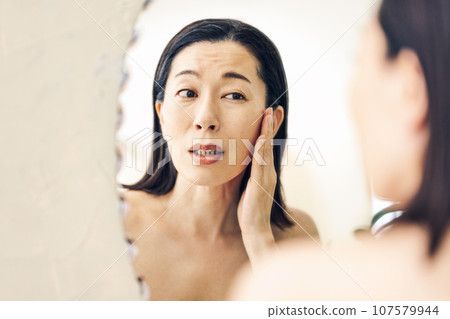 照鏡子的中年婦女關心自己的皮膚 107579944