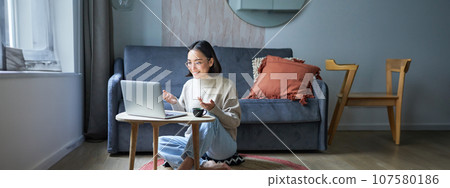 Portrait of young working woman, korean girl studying on remote online, talking to laptop, video chat, has conversation via computer application 107580186