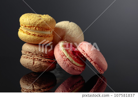 Delicious colorful macaroons on a black reflective background. Delicious colorful macaroons on a black reflective background. 107581837