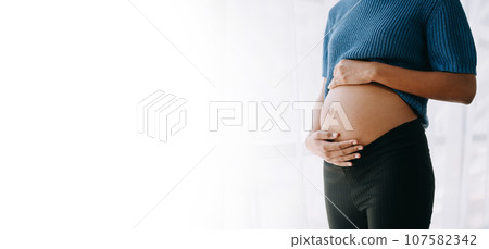 pregnant african american woman at home window white background. pregnant african american woman at home window white background. 107582342