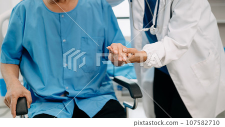 Asian physiotherapist helping elderly man patient stretching arm during exercise correct with dumbbell in hand during training hand in bed in clinic Asian physiotherapist helping elderly man patient stretching arm during exercise correct with dumbbell in hand during training hand in bed in clinic 107582710