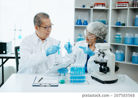 Two scientist or medical technician working, having a medical discuss meeting with Asian senior female scientist supervisor in the laboratory with online reading, test samples and innovation 107583568