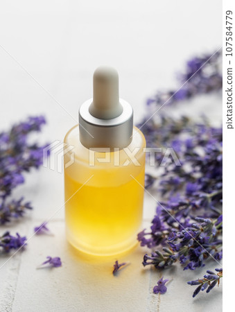 Lavender natural essential oil and fresh lavender on a white tile background. Lavender natural essential oil and fresh lavender on a white tile background. 107584779