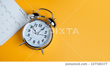 Top view of calendar and alarm clock on yellow background, planning for business meeting or travel planning concept 107586377