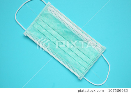 Surgical face mask on blue background protection against COVID-19 coronavirus. Healthcare and medical concept Surgical face mask on blue background protection against COVID-19 coronavirus. Healthcare and medical concept 107586983