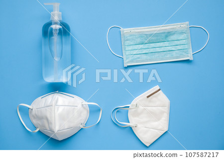 Alcohol hand sanitizer gel bottle with KN95 surgical face mask on blue background protection against COVID-19 coronavirus. Healthcare and medical concept Alcohol hand sanitizer gel bottle with KN95 surgical face mask on blue background protection against COVID-19 coronavirus. Healthcare and medical concept 107587217